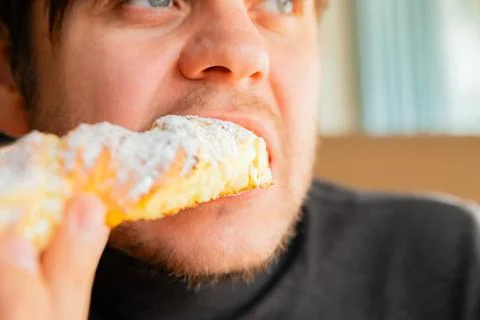 Man eats freshly long curd baked sweet pastry in bakery cafe. Tasty sweet Stock Photos