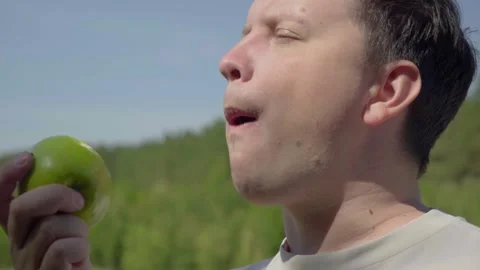 Man eats a green apple in the open air Video stock 222124109