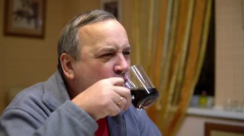 The man eats a hamburger and drinks soda. Man with hamburger at home. Stock Photos