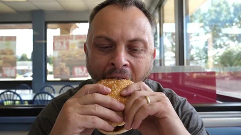Man eats hamburger burger sandwich at the fast food chain restaurant Stock Footage 80745836