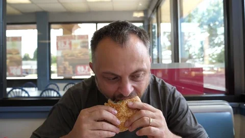 Man eats hamburger burger sandwich at the fast food restaurant Stock Footage 80746065