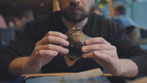 Man eats a hamburger in a cafe Stock Footage 84797432