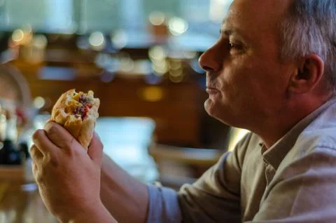 The man eats hamburger with pleasure. Stock Photos