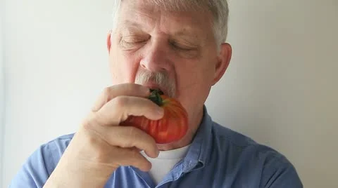 Man eats heirloom tomato Stock Footage 22370632