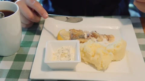 A man eats homemade fish and mashed potatoes with tartar sauce with a knife and Stock Footage 161037430