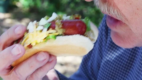 Man eats hot dog with cheese and relish Stock Footage 91447142
