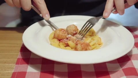 A man eats Italian pasta with chicken meatballs and tomato sauce. Video stock 161097293