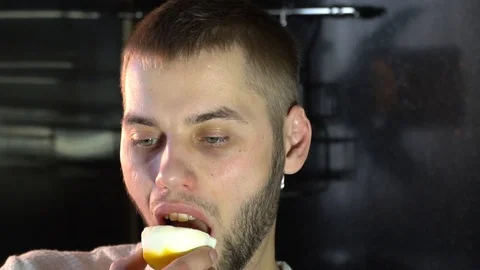 A man eats a juicy lemon wrinkling his face, sour Stock Footage 86149011