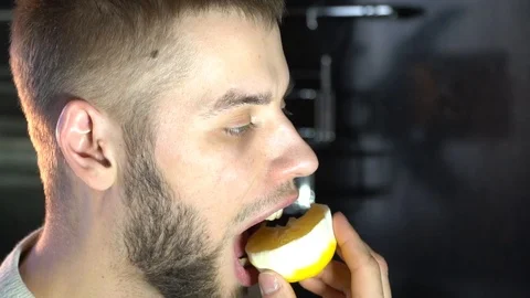 A man eats a juicy lemon wrinkling his face, sour Stock Footage 86149062