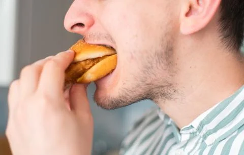 A man eats junk food, a close-up. Guy bites chicken burger Foto stock