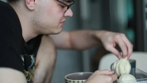 A man eats khinkali deliciously. Young man having dinner with a Georgian dish Stock Footage 205068407