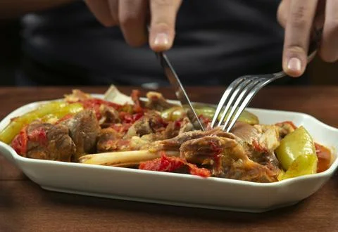 Man eats lamb stew on the bone with vegetables. Khashlama is popular Armenian Stock Photos