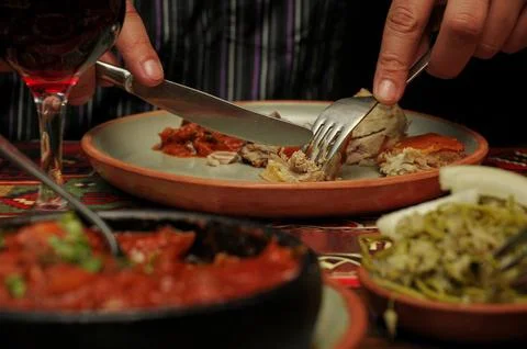Man eats lamb stew on bone with vegetables. Khashlama is popular Armenian dis Stock Photos