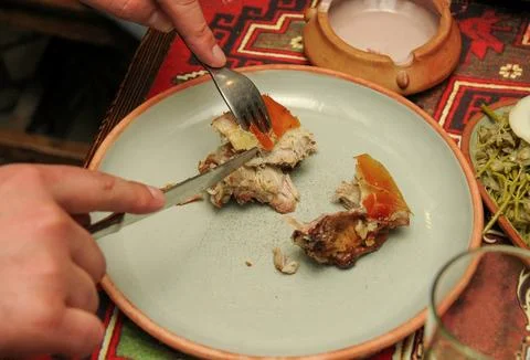 Man eats lamb stew on bone with vegetables. Khashlama is popular Armenian dis Stock Photos