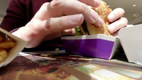 A man eats mcdonalds a bacon burger in traditional dining 動画素材 131221577