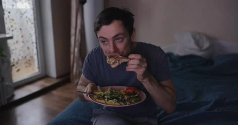 Man eats meat and watches tv at home Stock Footage 147556082
