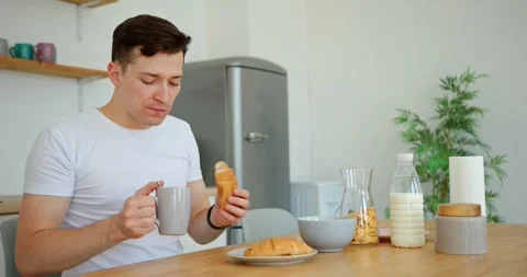 A man eats milk and a croissant for breakfast. He is late for work Stock Footage 279405783