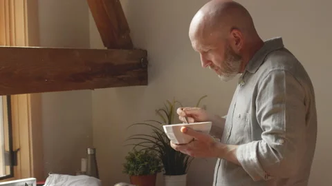 Man eats noodles while video chatting with a colleague working from home Video stock 133297243