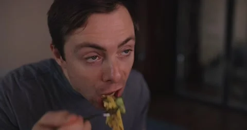 Man eats pasta and watches tv at home Stock Footage 147555918