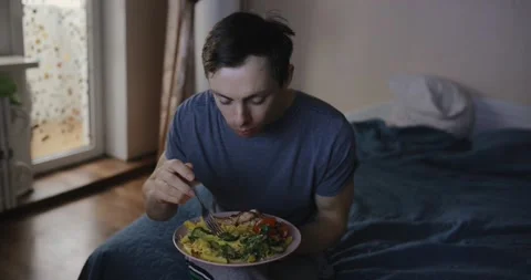 Man eats pasta and watches tv at home Stock Footage 147556032