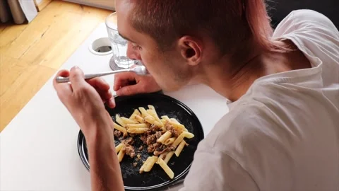 Man eats pasta from black plate top view. Pasta mixed with meat and sauce o.. Stock Footage 318902695