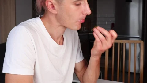 Man eats pasta with hands in home kitchen. Pasta sticks to fingers and look.. Video stock 318902632