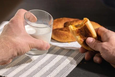 Man eats pie and drinks milk. first-person photo Stock Photos