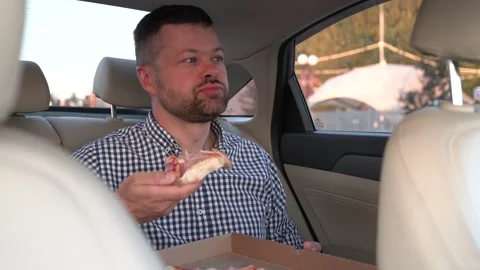 Man eats pizza in back seat of luxury car Stock Footage 204942217