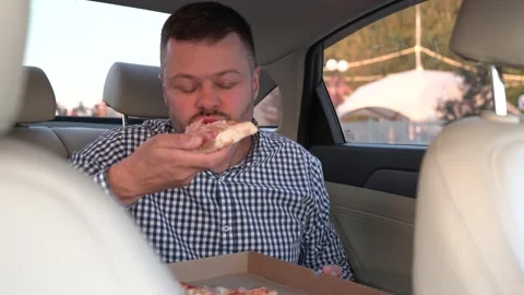 Man eats pizza in back seat of luxury car Stock Footage 204942258