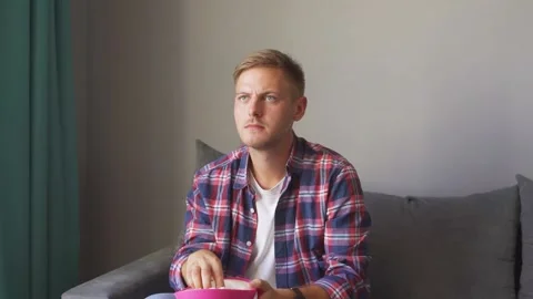 Man eats popcorn and watches tv. Stock Footage 221398985