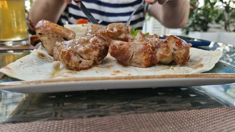 A man eats pork kebab in a restaurant. 動画素材 246854912