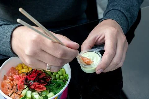 A man eats a raw organic poke-a bowl with rice, fish and vegetables close-u.. Stock Photos