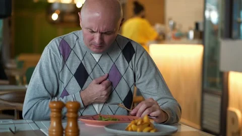 Man eats in a restaurant and begins to cough and gasp Stock Footage 143425020