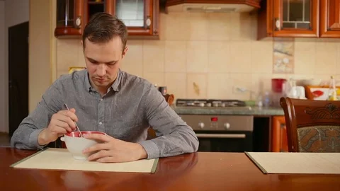 Man eats rice and cutlet in his kitchen at home Stock Footage 74432333