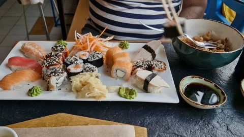 A man eats rolls, sushi in a cafe. Rest, lunch at the restaurant. Stock Footage 203883771