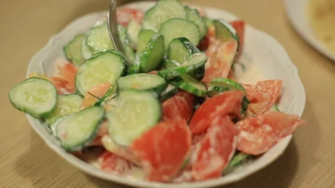 A man eats a salad of fresh cucumbers and red tomatoes with white sauce 스톡 동영상 93063711