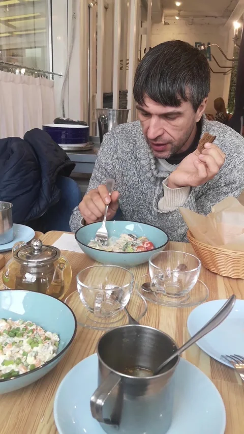 A man eats seafood salad with a fork while holding rye bread Vídeos de archivo 348779541