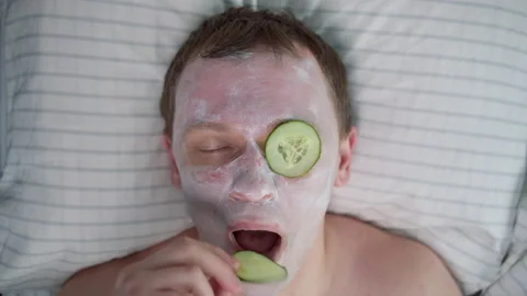 A man eats a slice of cucumber that lay before his eyes Stock Footage 135752269