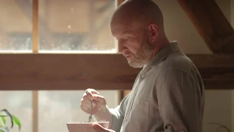 Man eats a steaming bowl of noodles in front of his office window Video stock 133294056
