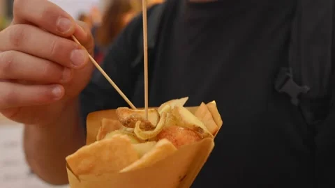Man eats street Sicilian fried food, potatoes and panelle in paper cone stick Stock Footage 217558919