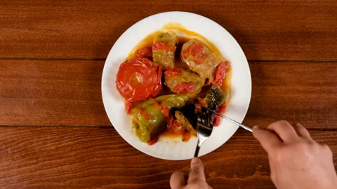 A man eats summer dolma, cabbage, eggplants, peppers and tomatoes stuffed with m Stock Footage 283361151