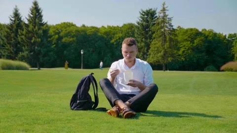 Man eats vegetarian lunch with an ecologic package, frowning and showing dislike Stock Footage 141719803