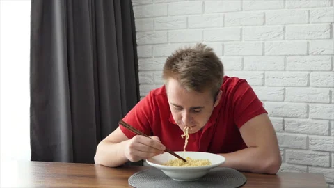 A man eats vermicelli, fast food pasta. The guy eats noodles funny. Stock Footage 195127329