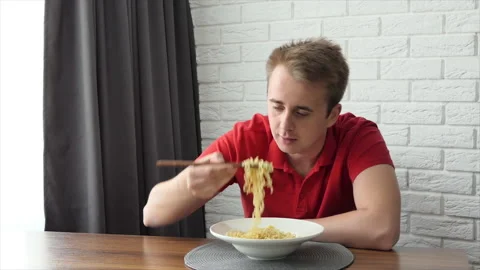 A man eats vermicelli, fast food pasta. The guy eats noodles funny. Stock Footage 195828053