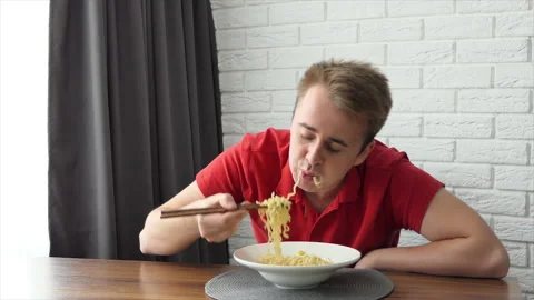 A man eats vermicelli, fast food pasta. The guy eats noodles funny. Stock Footage 196008160