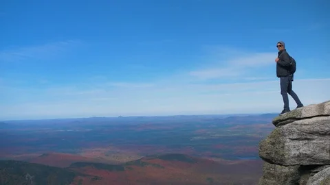 Man on Edge of Cliff of Mountain Overlooking Wilderness Stock Footage 102401350