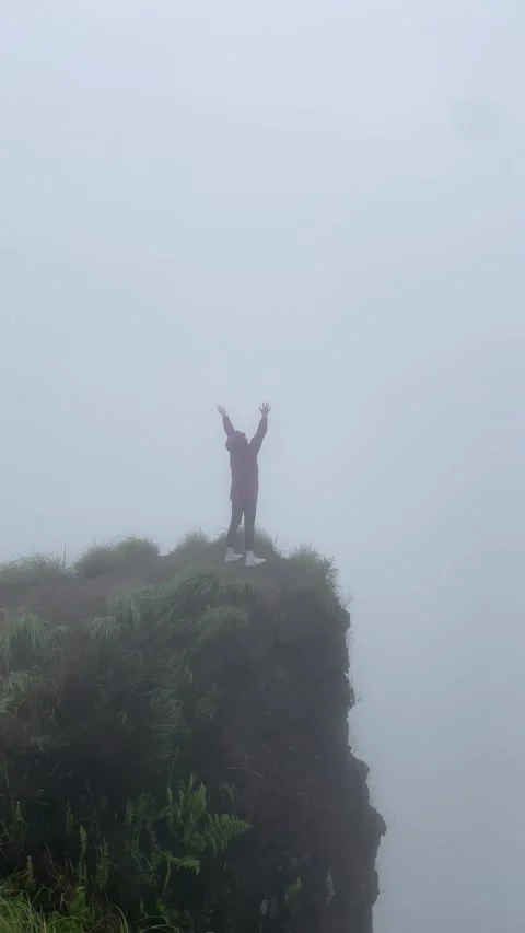 Man on the edge of a cliff raises his hands up Video stock 283816598