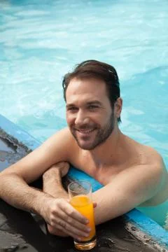 Man in the edge of the pool drinking juice Stock-Fotos