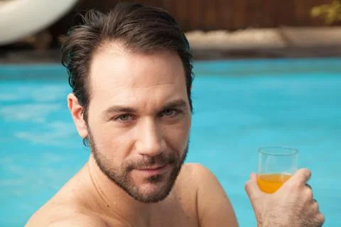 Man in the edge of the pool drinking juice 写真素材