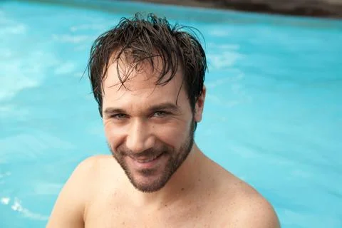 Man in the edge of the pool using a tablet Stock Photos